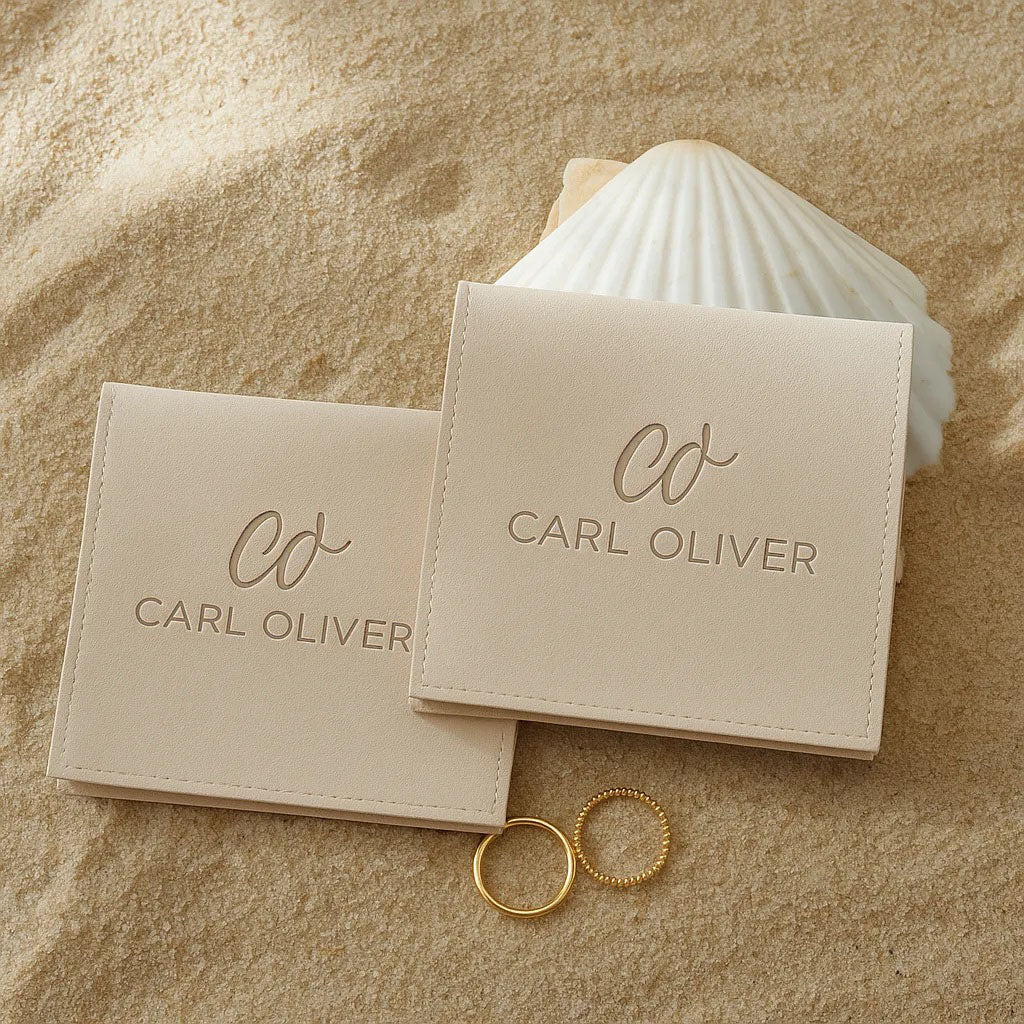 Beige jewelry box with 'Carl Oliver' branding on a sandy background