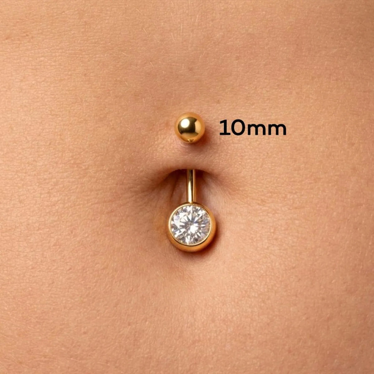 Close-up of a belly button with a gold-tone navel piercing showing a 10mm ball stud above and a lower barbell with a clear gemstone below, with '10mm' text overlay.