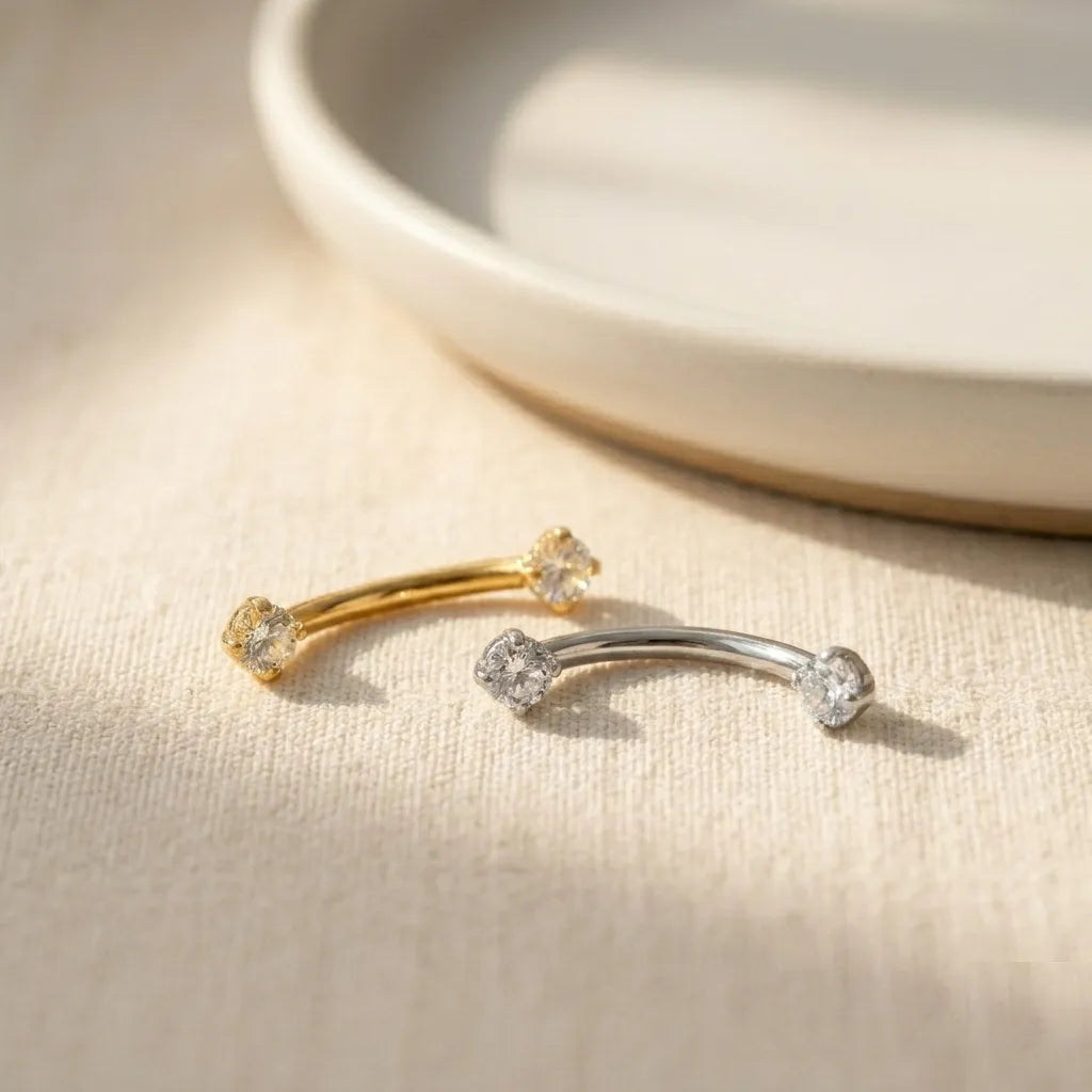 Gold and silver earrings with clear stones on a beige surface