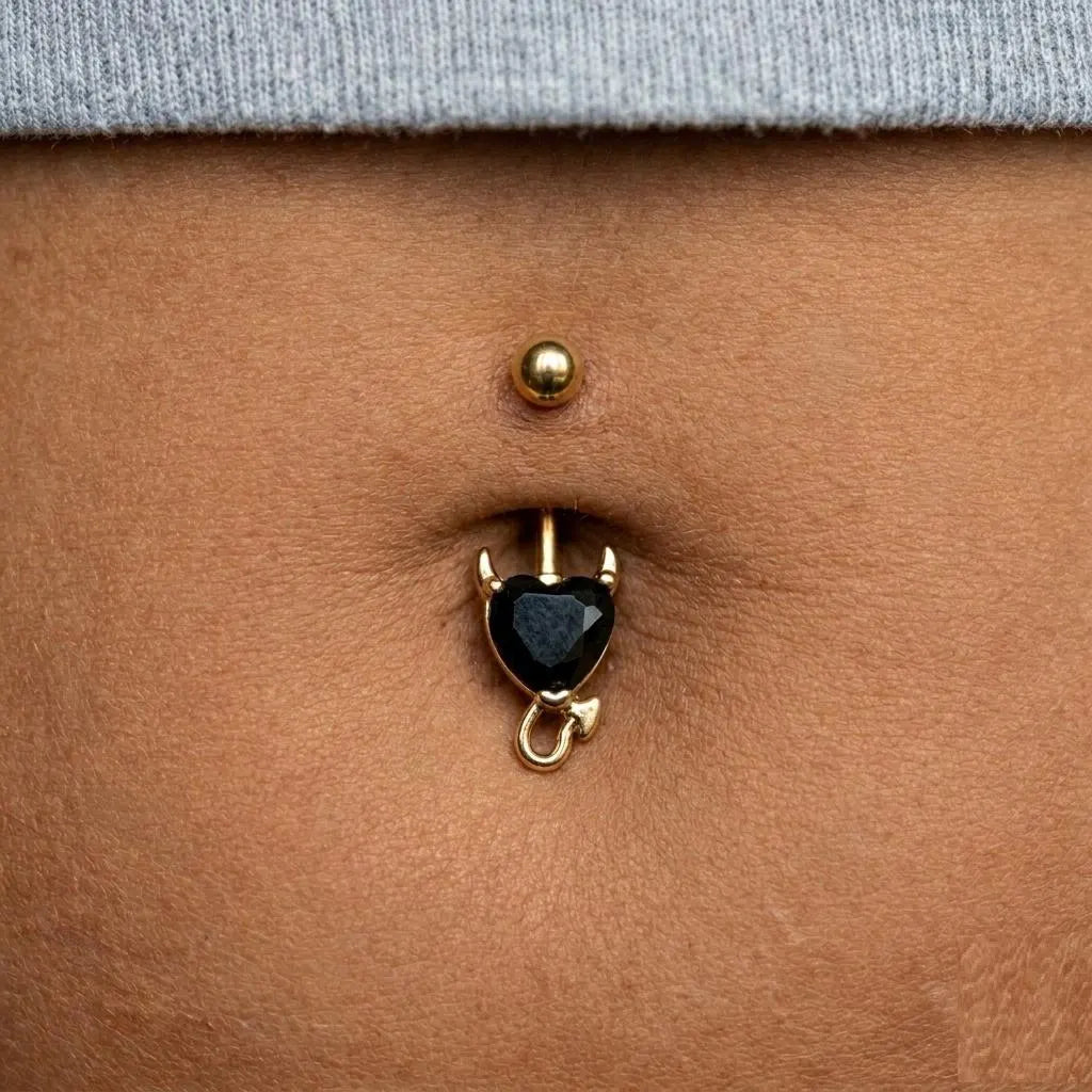 Belly button ring with black gemstone and gold setting on a person's belly.