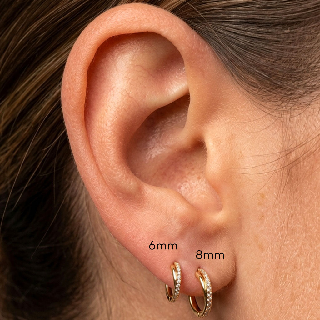 Close-up of an ear with two gold hoop earrings labeled 6mm and 8mm.