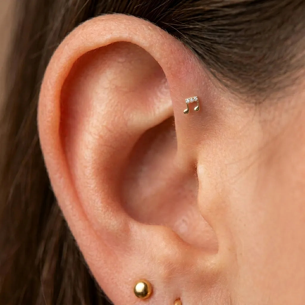 Close-up of an ear with gold and silver earrings.