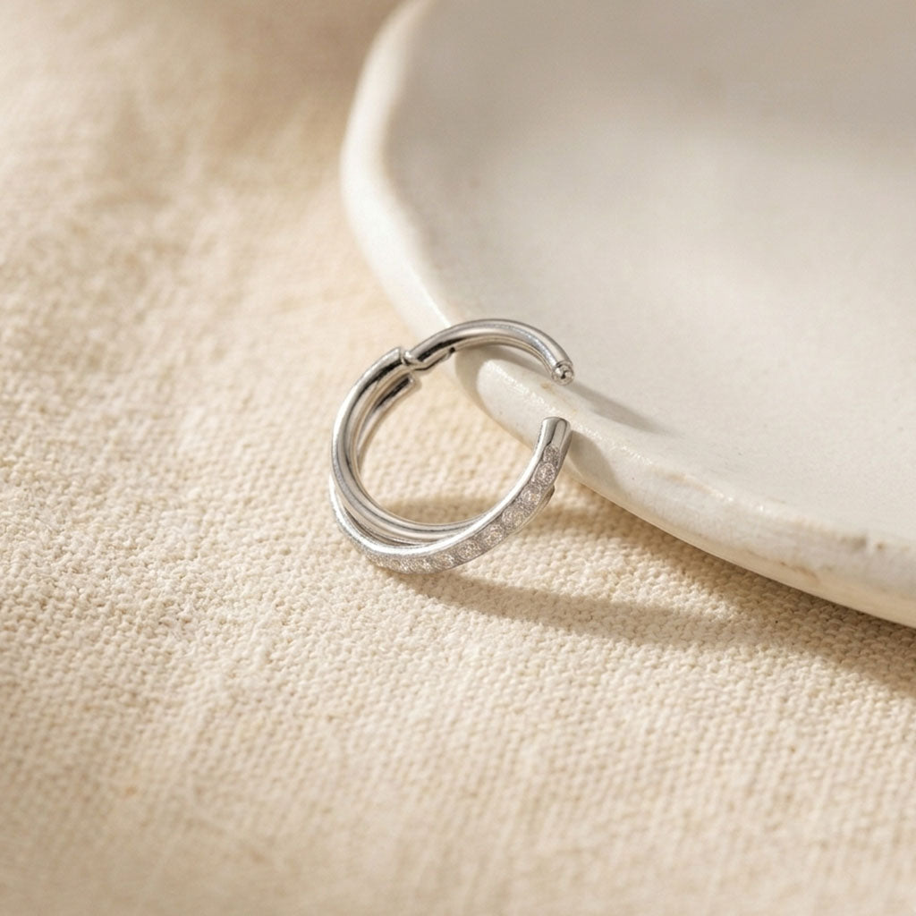 Silver hoop earring on a beige fabric background