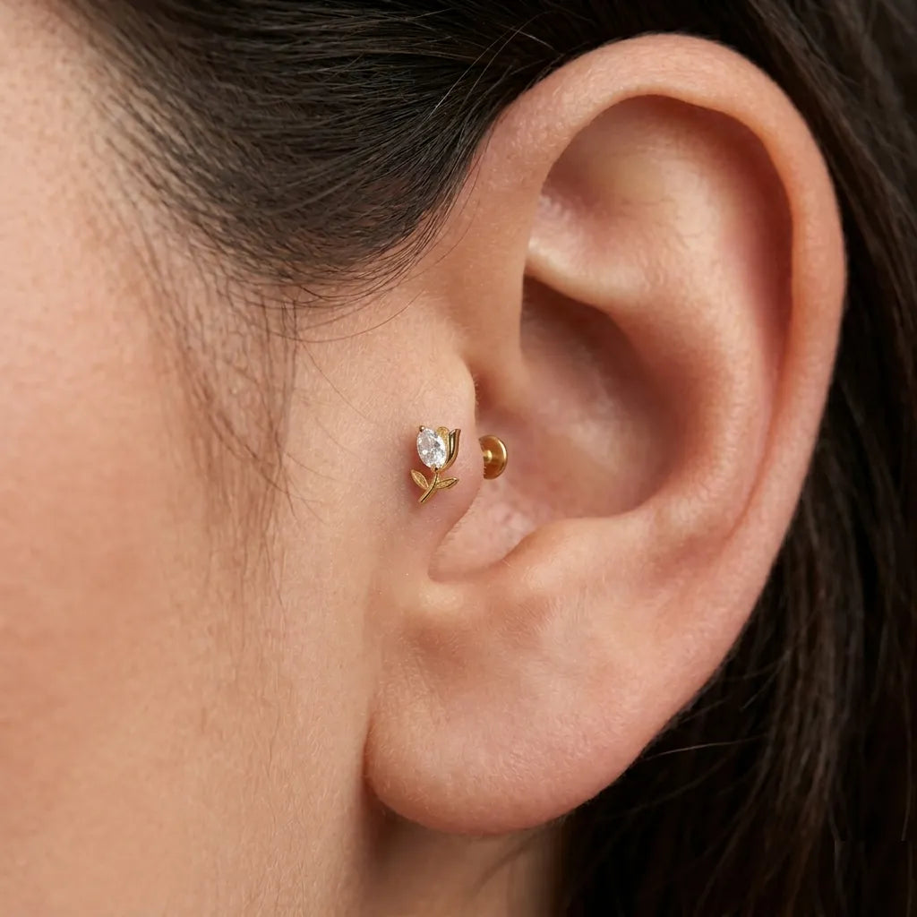 Close-up of an ear wearing a gold earring with a clear gemstone.