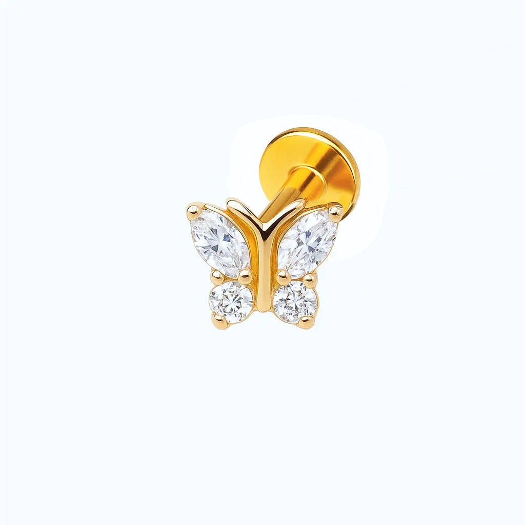 A gold-colored titanium piercing featuring a butterfly design with clear crystals.