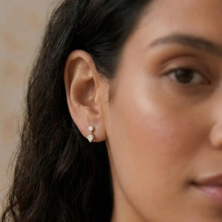 Close-up of a woman wearing a diamond earring with a neutral background