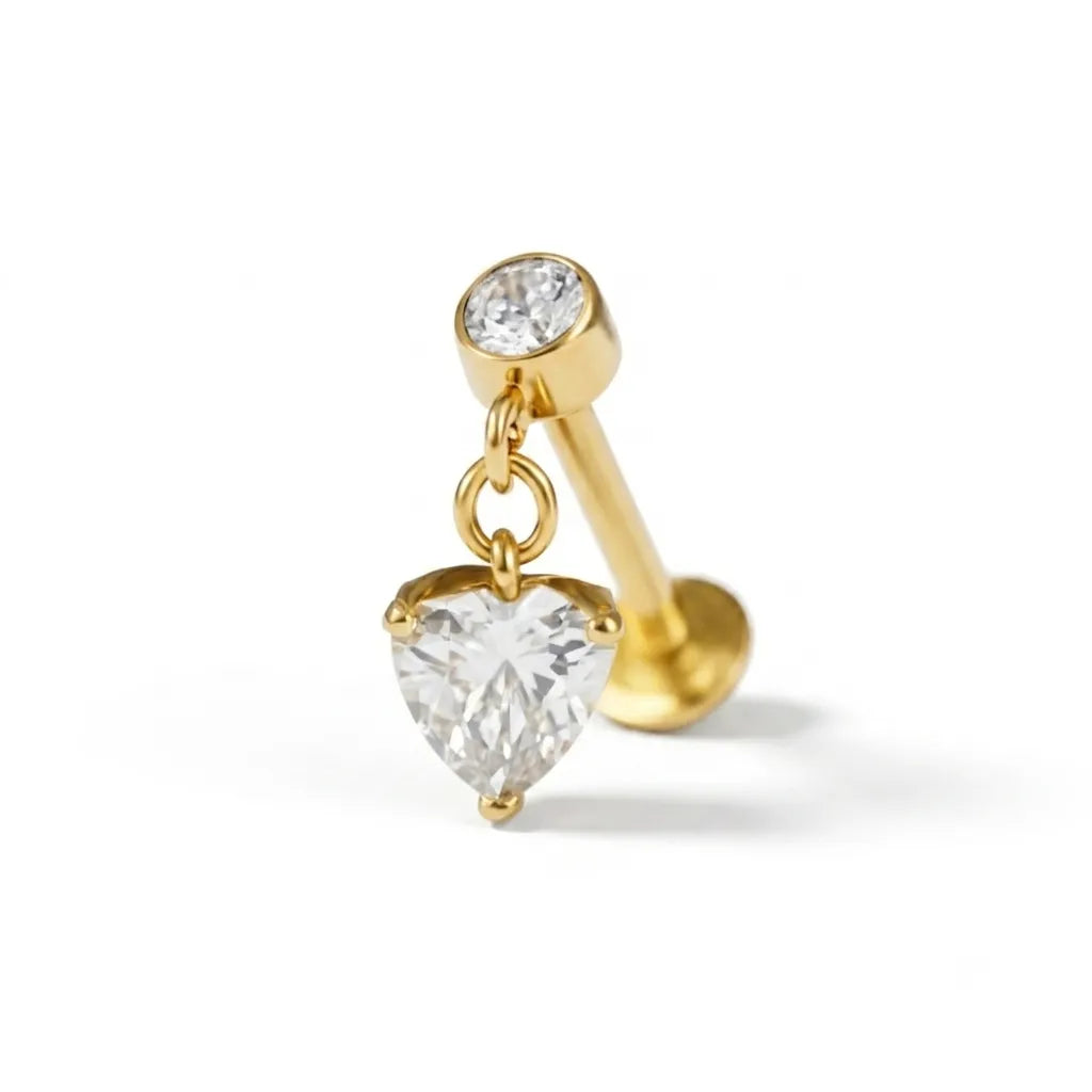 Gold belly button ring with heart-shaped and round clear gemstones on a white background