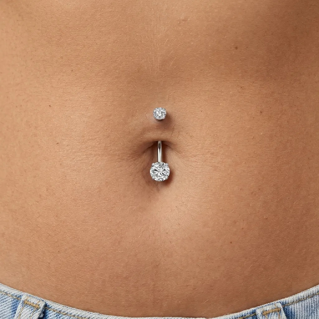 Close-up of a person's belly button with two silver belly buttons on a beige background.