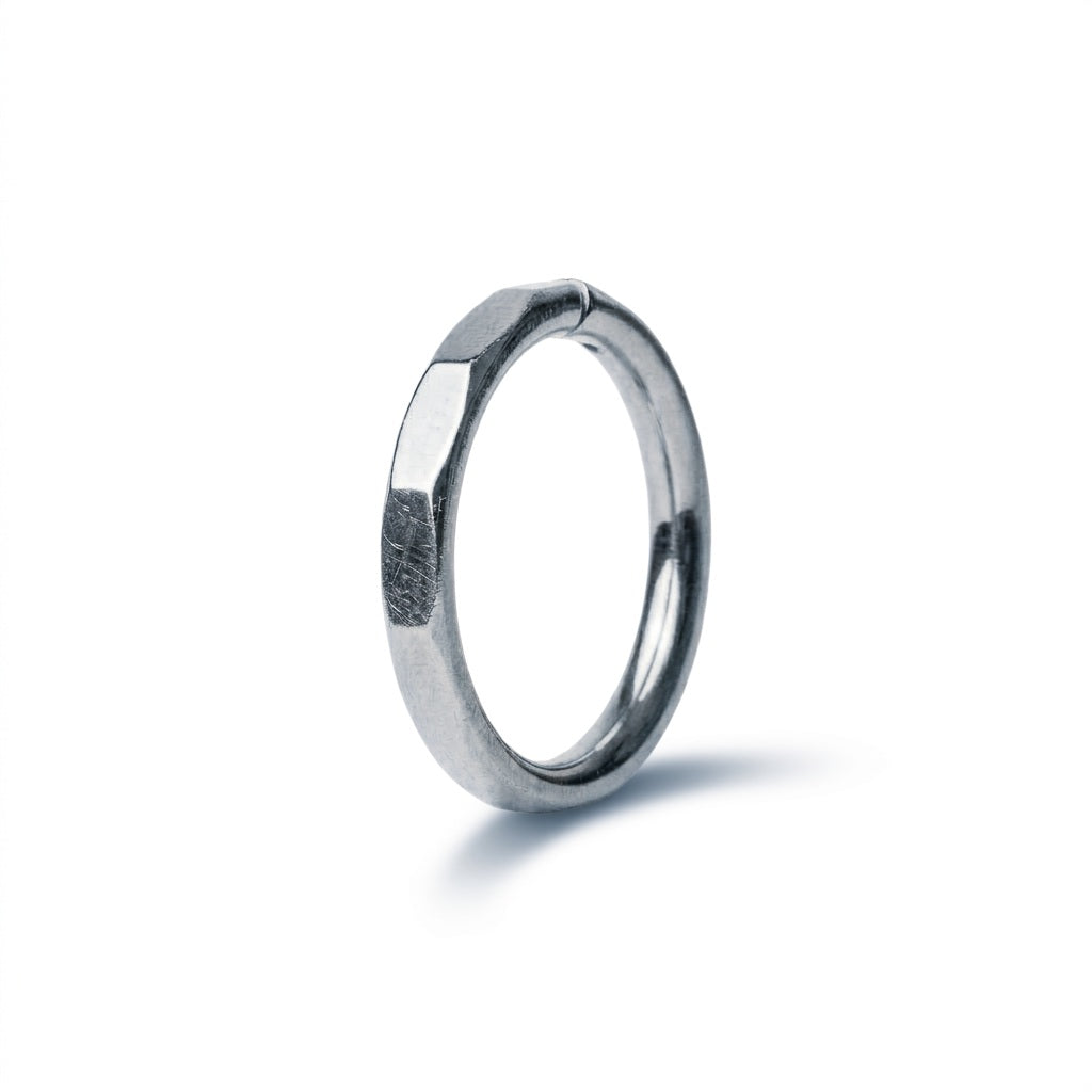 A silver-toned metal ring with a hexagonal, knurled texture on its outer surface, shown standing upright on a clean white background with a soft shadow.