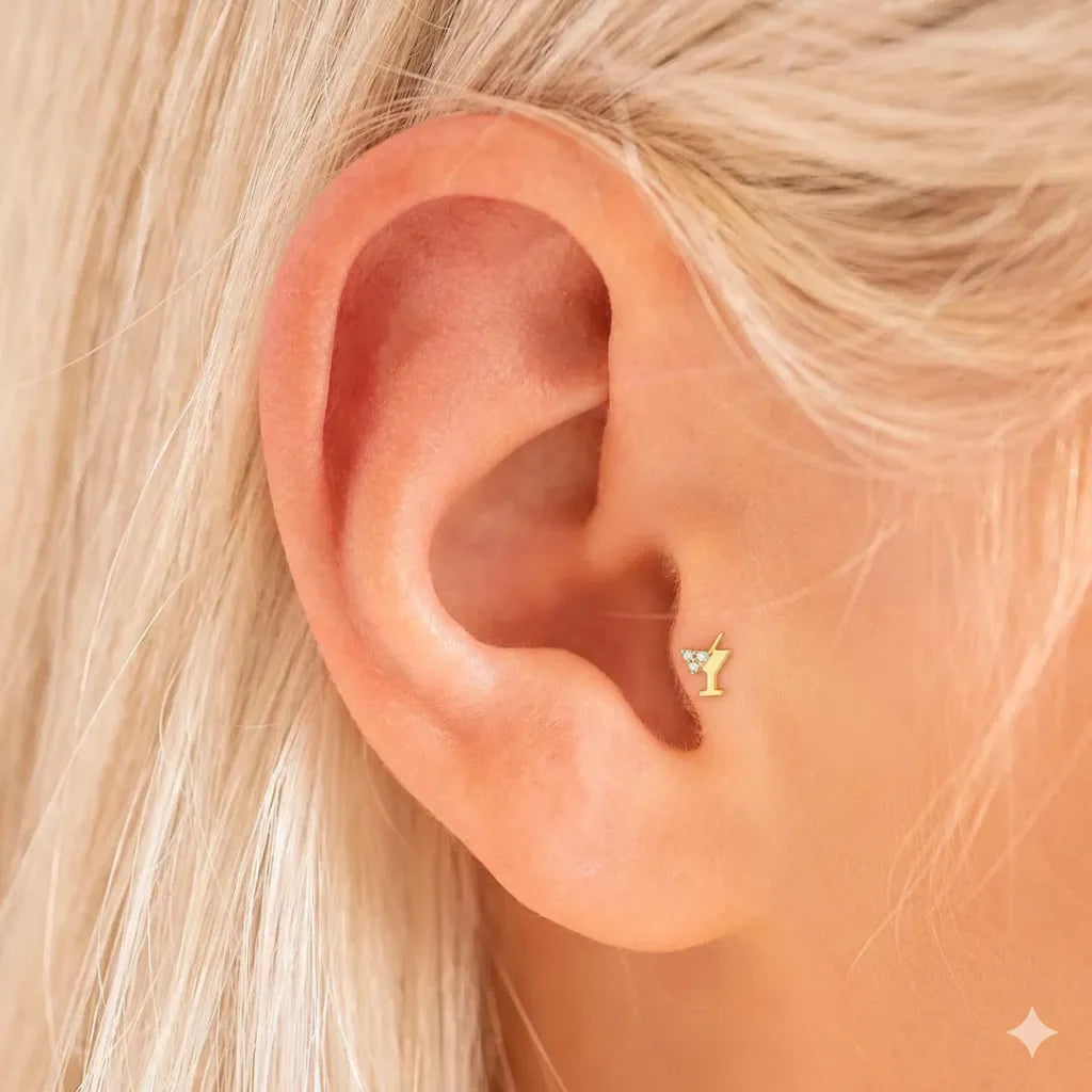 Close-up of an ear wearing a gold earring with a small gemstone.