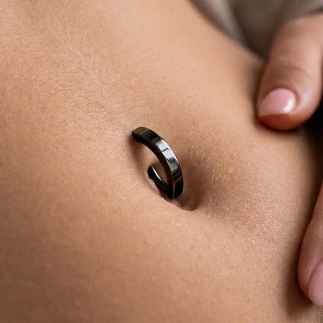 Close-up of a person wearing a black belly ring on their finger.