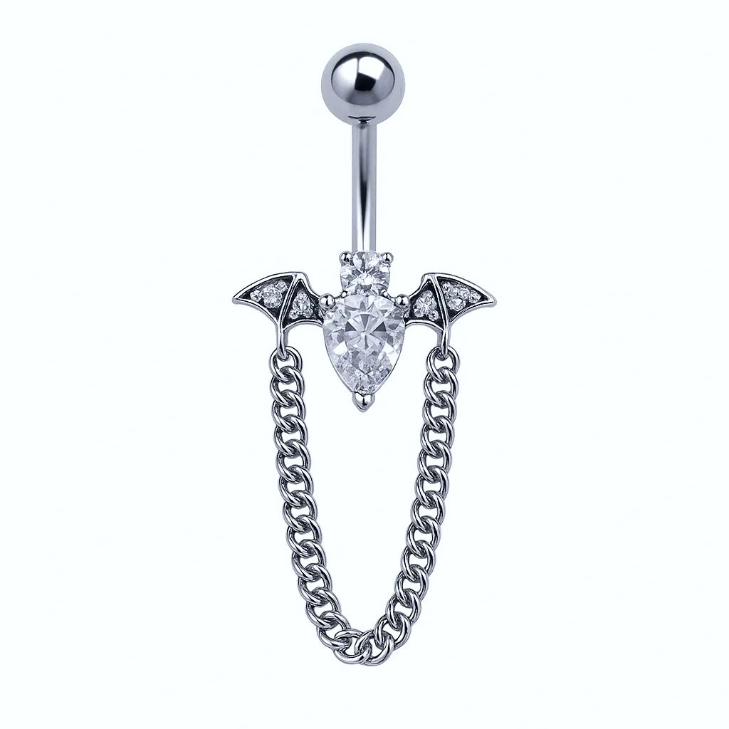 A silver surgical steel belly piercing with a crystal encrusted bat design and a chain.