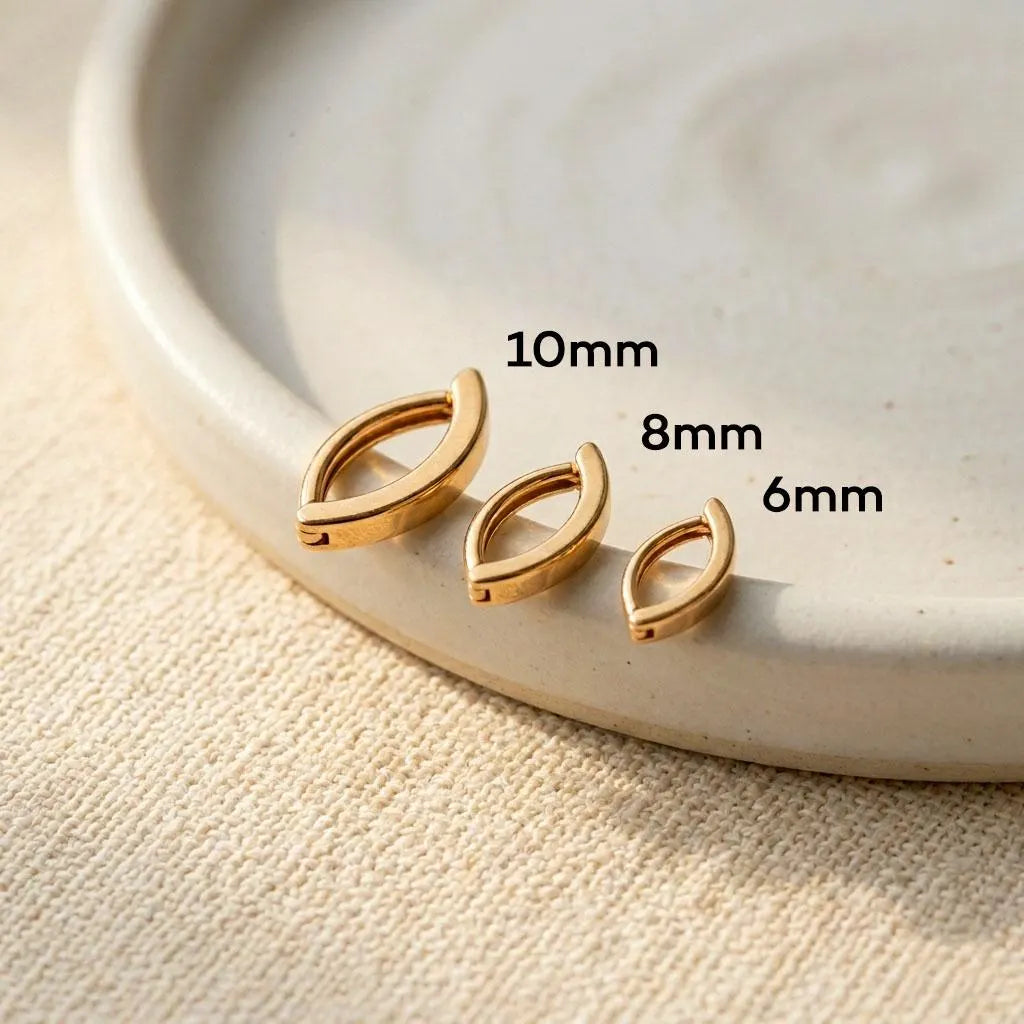 Gold leaf-shaped belly bars with size measurements on a beige surface