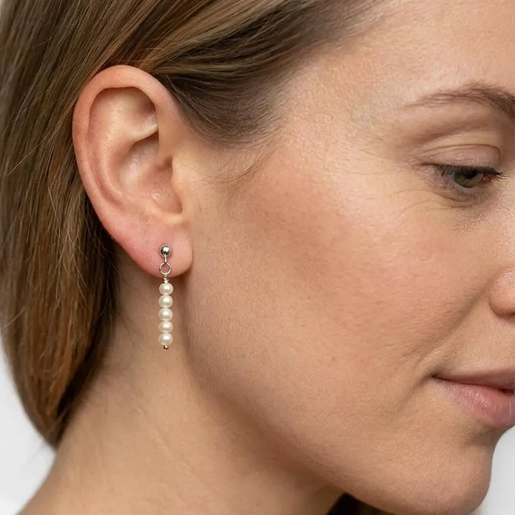 Close-up of Lys Doré silver pearl drop stud earrings on model's ear