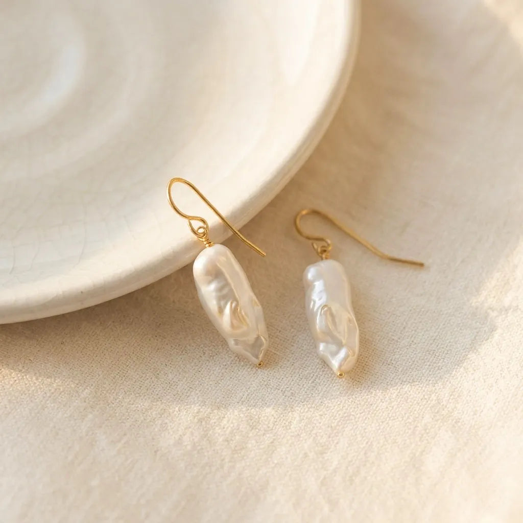 Side angle of Perla Opaline hook earrings catching natural light to reveal the subtle iridescent lustre of the pearls