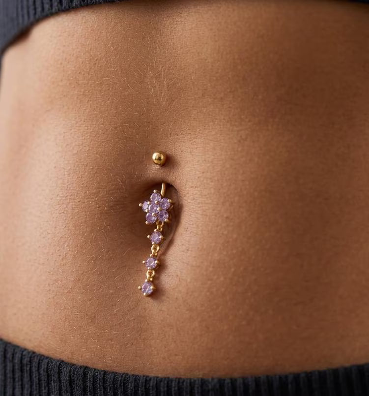 Close-up of a belly button ring with floral design on a person's skin.