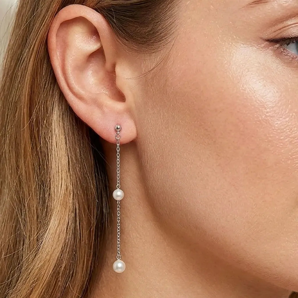 Close up of a woman wearing silver long chain pearl drop earrings to show length