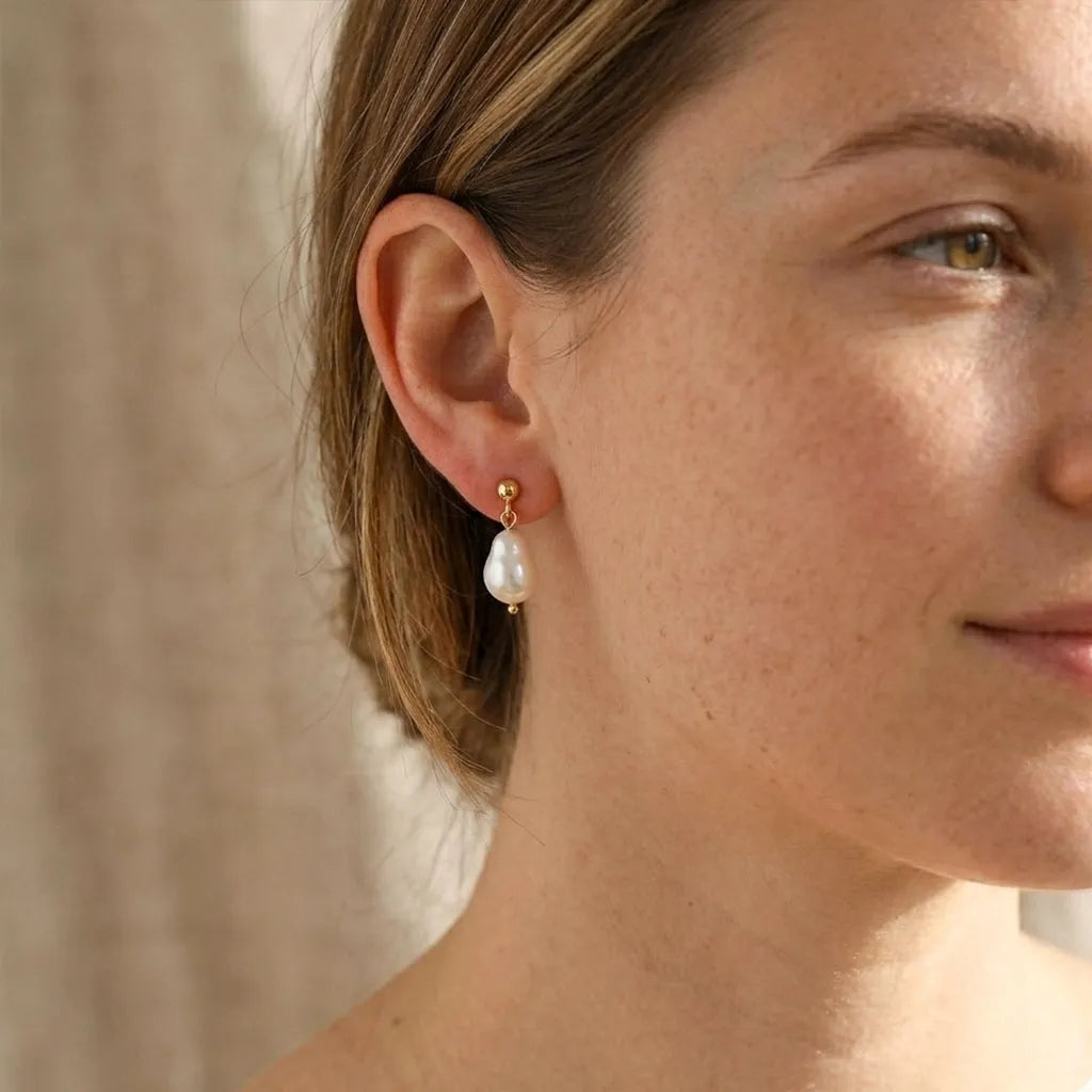 Model wearing Vita Perlata gold double pearl drop stud earrings, face view