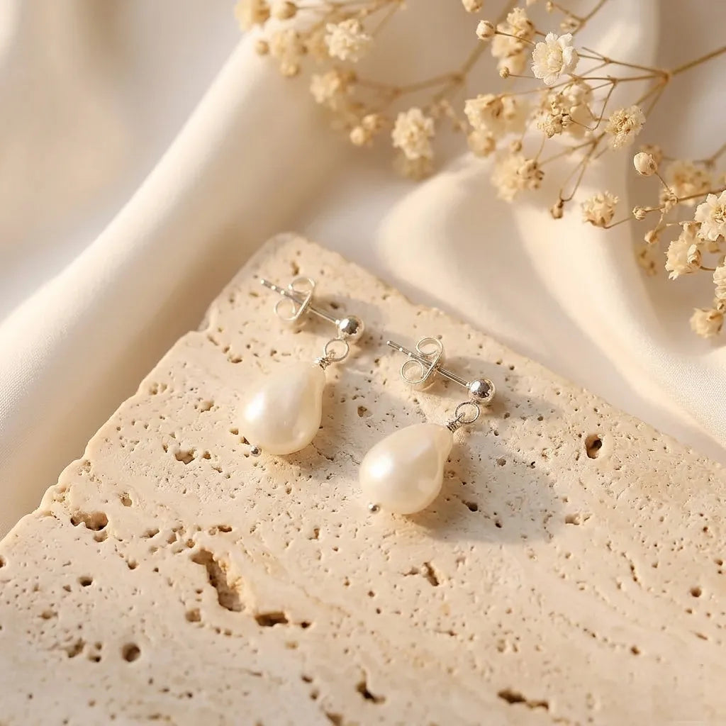 Vita Perlata silver baroque pearl drop earrings flatlay on neutral marble background