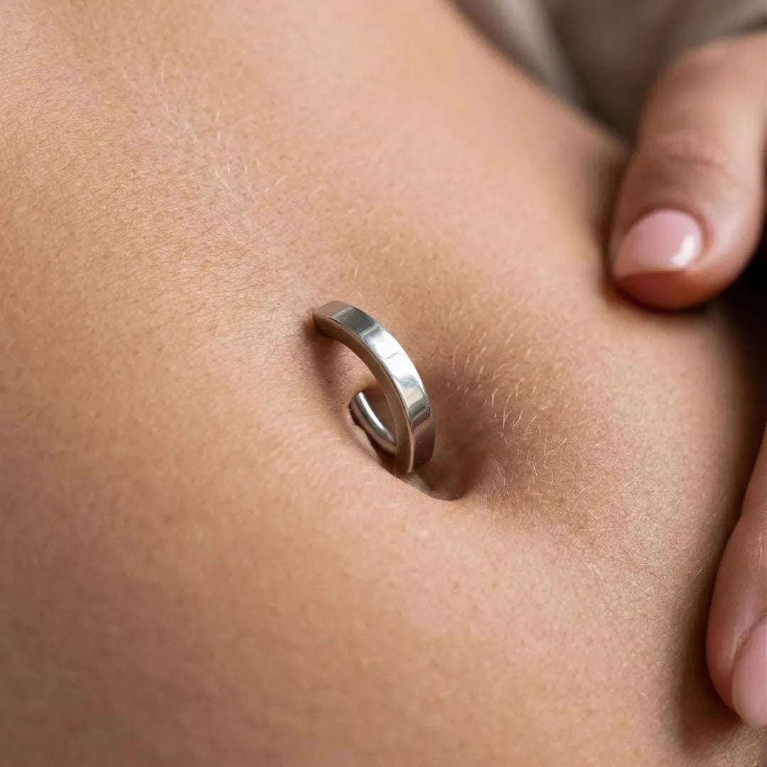 Silver belly button ring on a person's belly button.