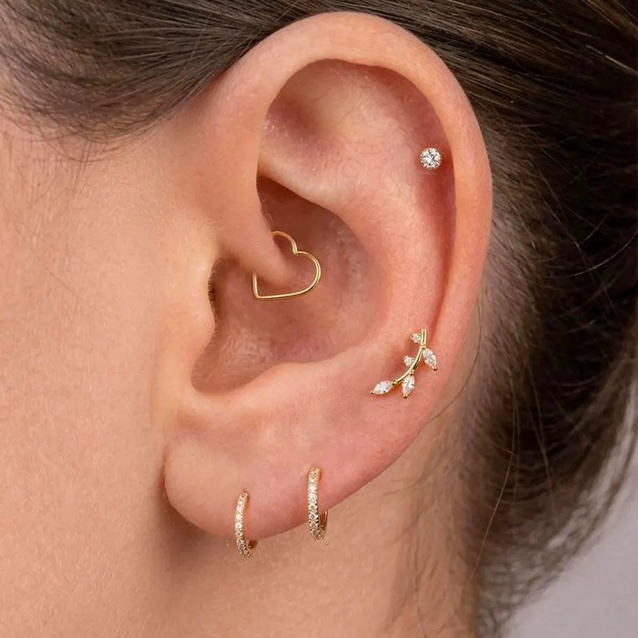 Close-up of an ear with multiple gold and diamond earrings.
