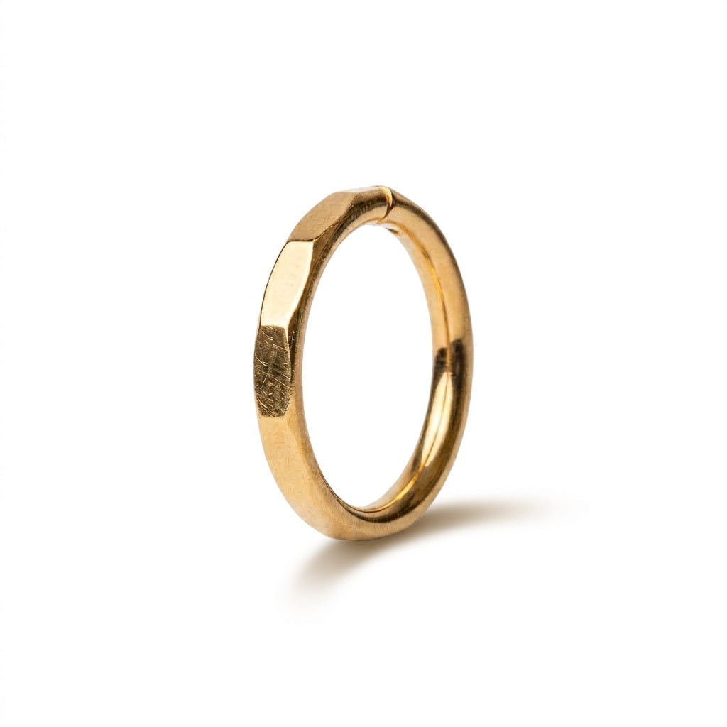 A gold-toned metal ring with a distinctive hexagonal, faceted texture, shown standing upright on a clean white background with a soft shadow.