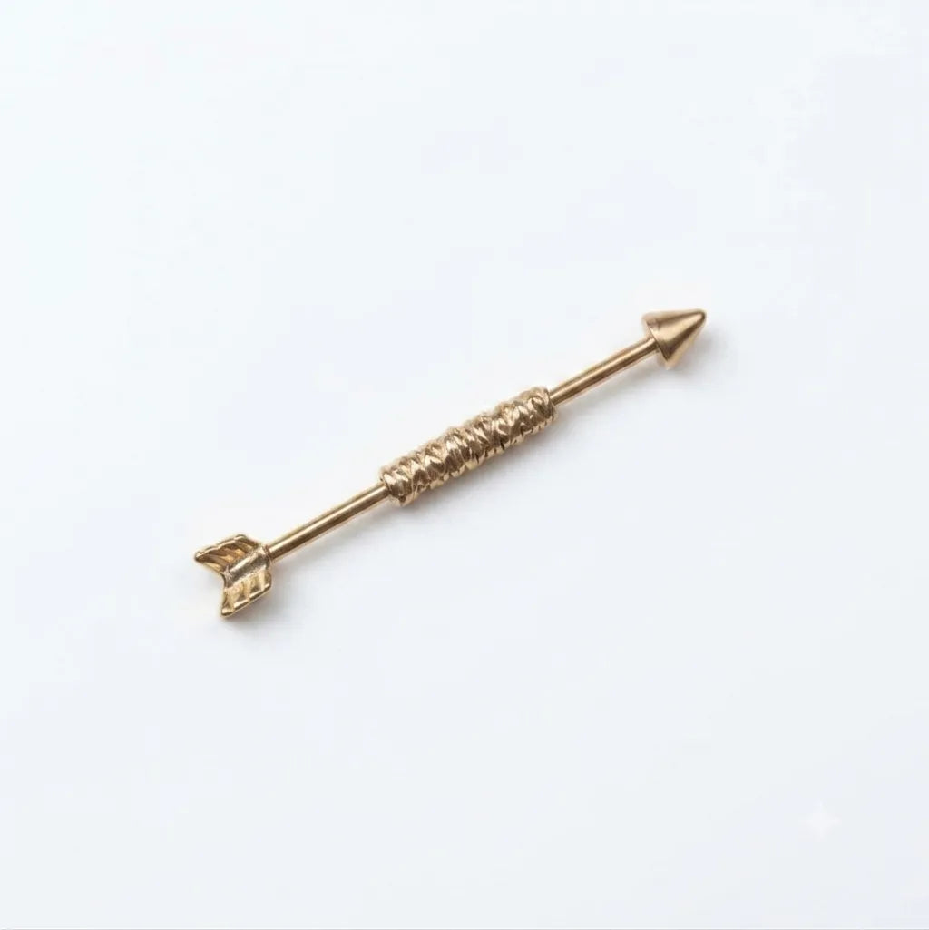 Gold arrow-shaped jewelry piece on a white background