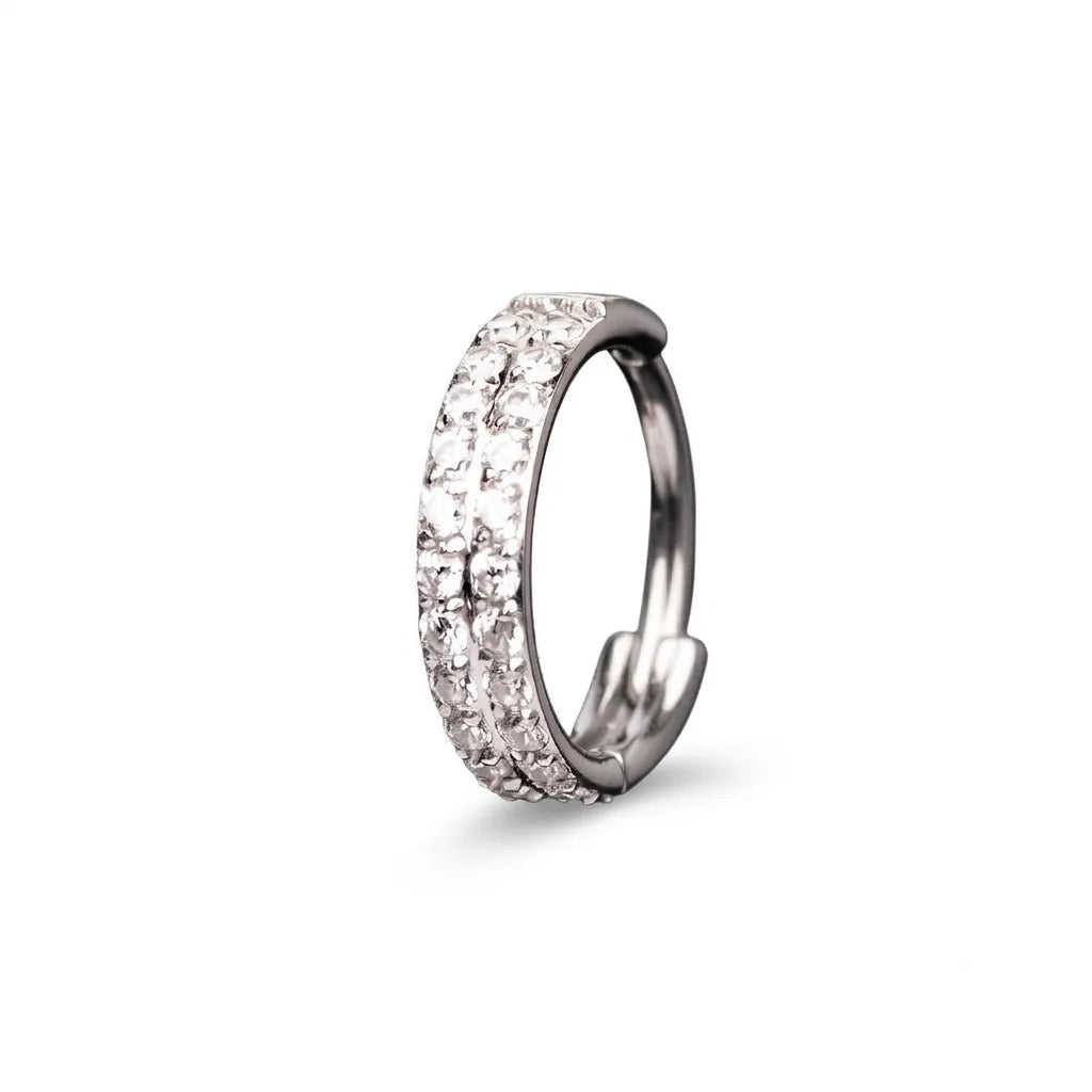 A silver-toned huggie hoop ring with two rows of clear pavé-set stones, shown on a clean white background.
