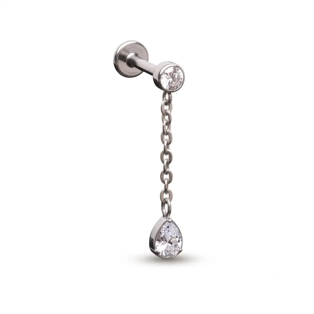 A silver-toned labret piercing stud with a short chain dangle and a teardrop-shaped clear gemstone, shown on a plain white background.