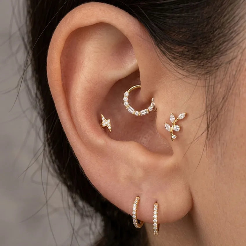 Close-up of an ear wearing multiple diamond earrings against a neutral background