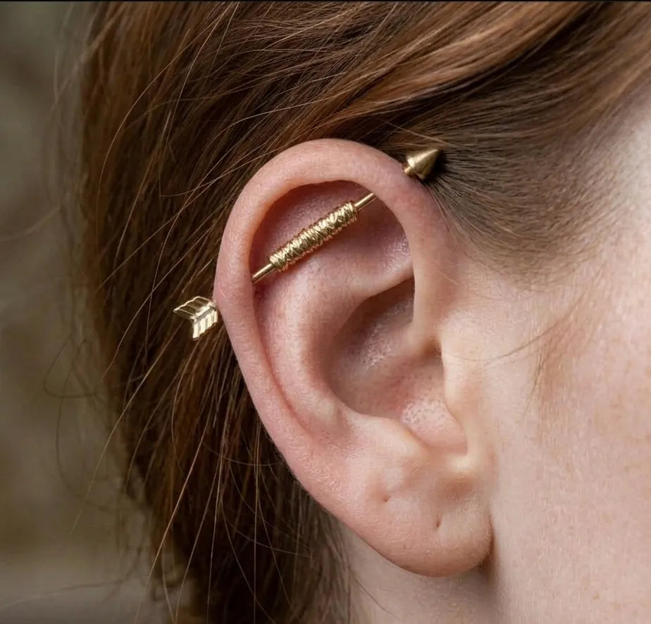Close-up of a person's ear wearing gold ear cuffs with a blurred background.
