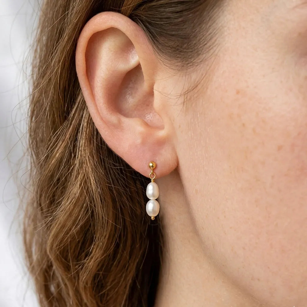 Model wearing Fleur Celeste gold freshwater pearl drop stud earrings, side profile