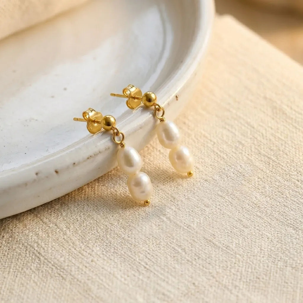 Detail view of Fleur Celeste gold pearl stud drop earrings showing pearl strand and butterfly back