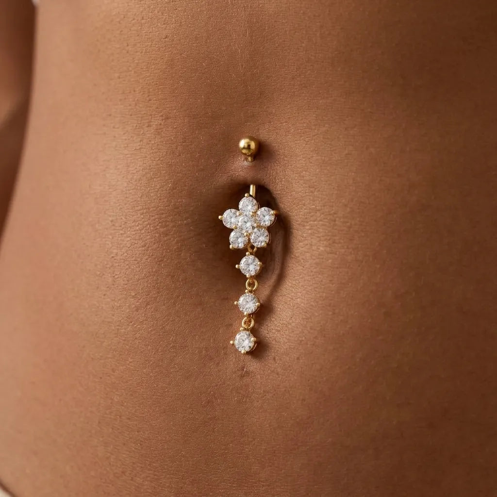 Gold belly button ring with floral design on a person's belly