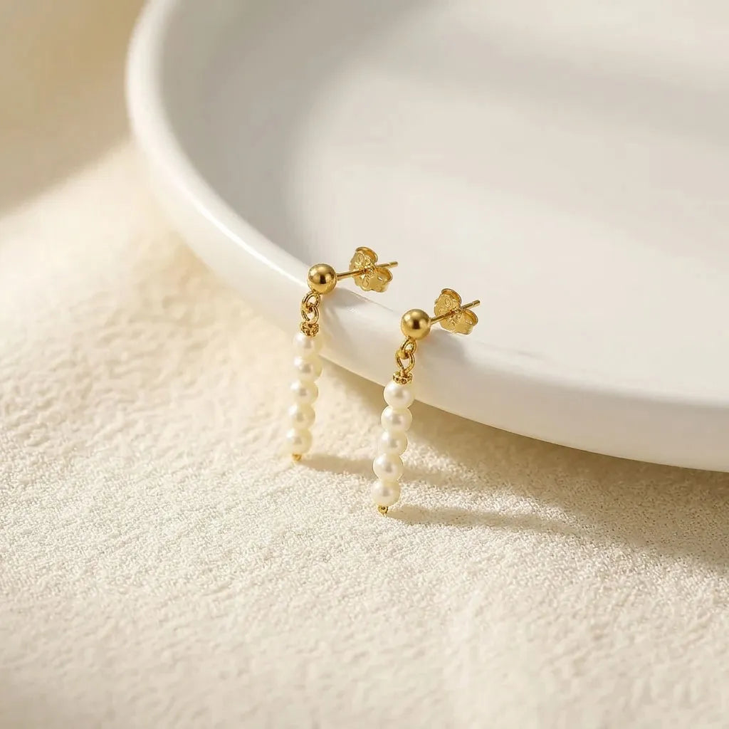 Lys Doré 14k gold stud baroque freshwater pearl drop earrings on white ceramic dish