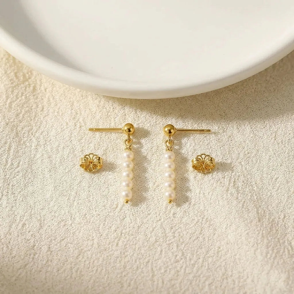 Close-up of Lys Doré gold baroque pearl drop earrings showing gold bead connector detail
