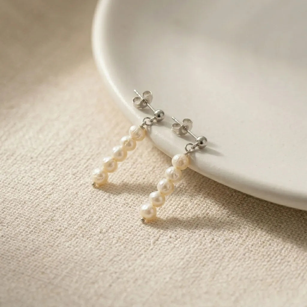 Pearl earrings on a white plate with a beige background