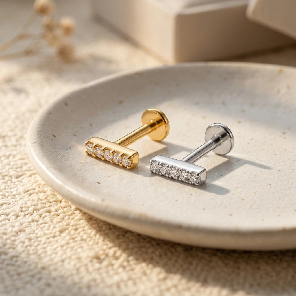 Gold and silver CZ bar tragus piercing flat back labret studs on ceramic dish