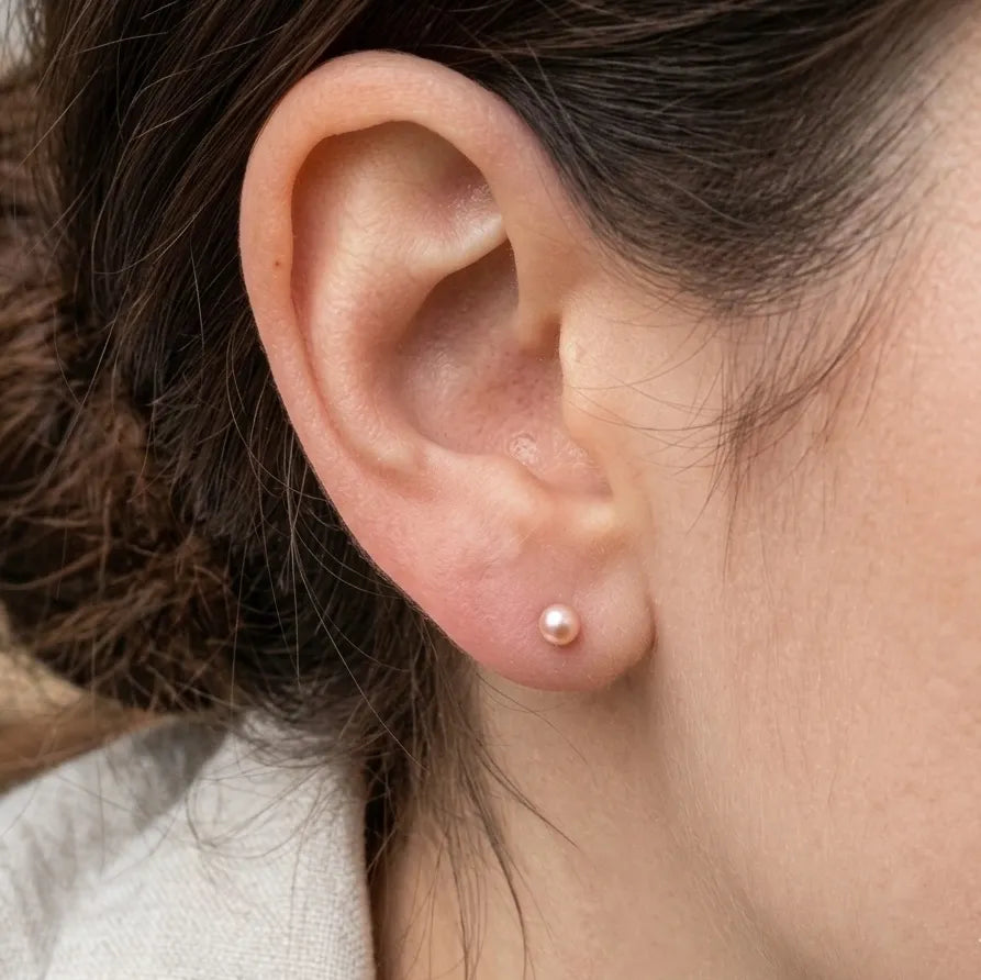 Close-up of an ear wearing a small pearl earring with blurred background