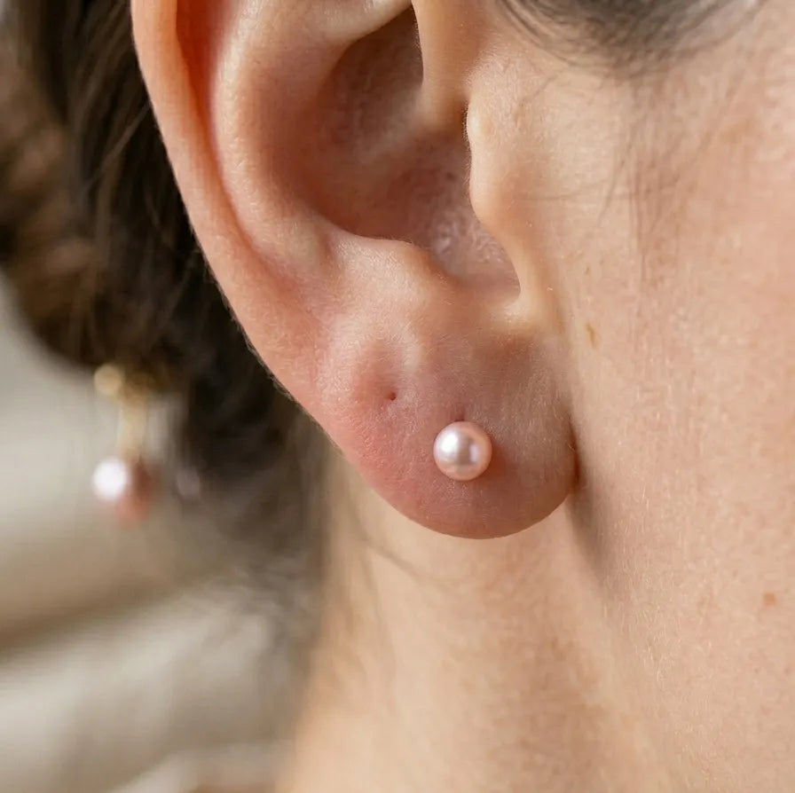 Close-up of an ear with a pearl earring on a blurred background