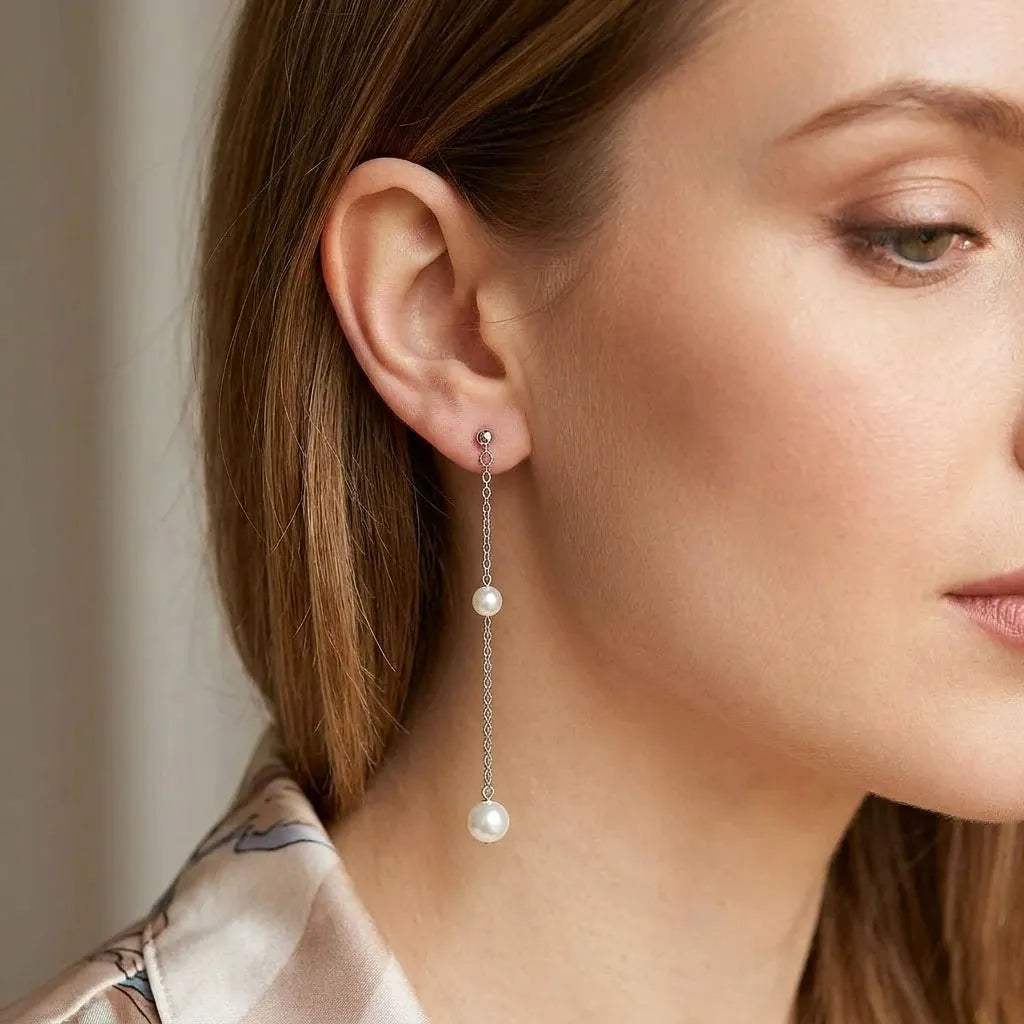 Side profile shot of a woman wearing silver chain pearl earrings to show the elegant drop length
