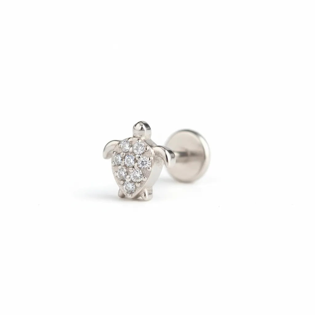 Silver turtle-shaped earring with clear gemstones on a white background