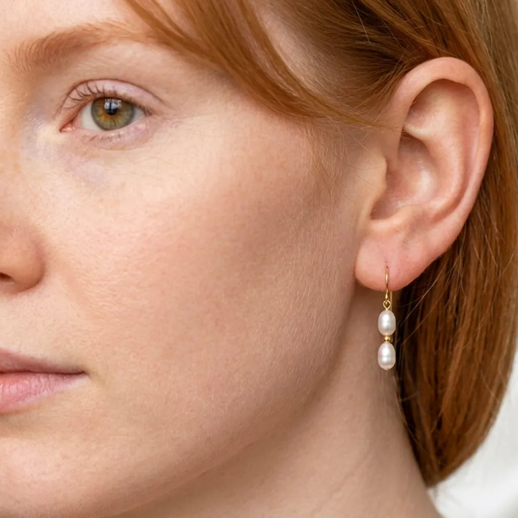 Close-up of Solea Alba double pearl drop earrings worn on model's ear