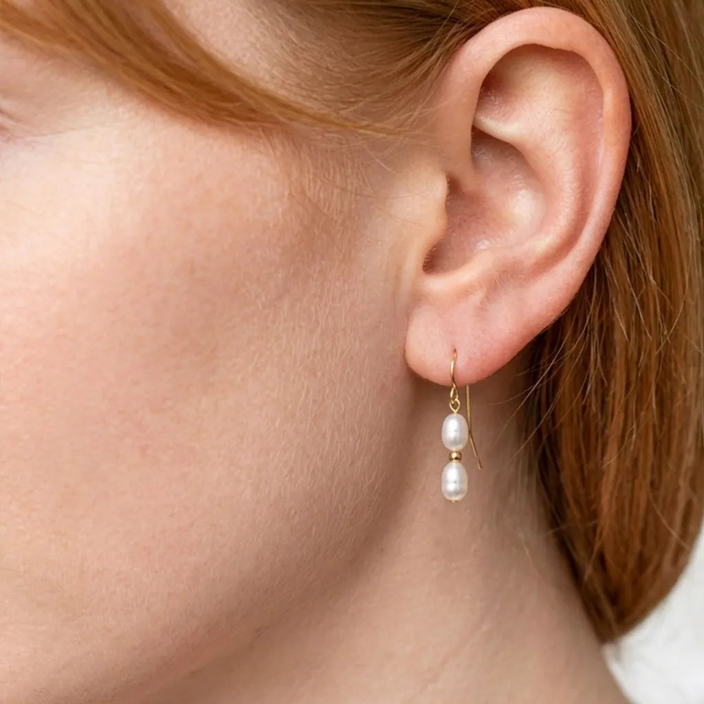 Model wearing Solea Alba gold filled double pearl drop earrings, front-facing portrait