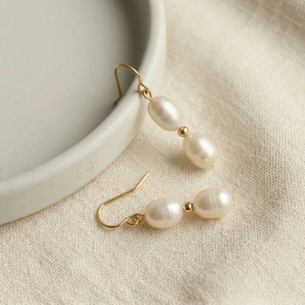 Pearl earrings with gold hooks on a beige fabric background