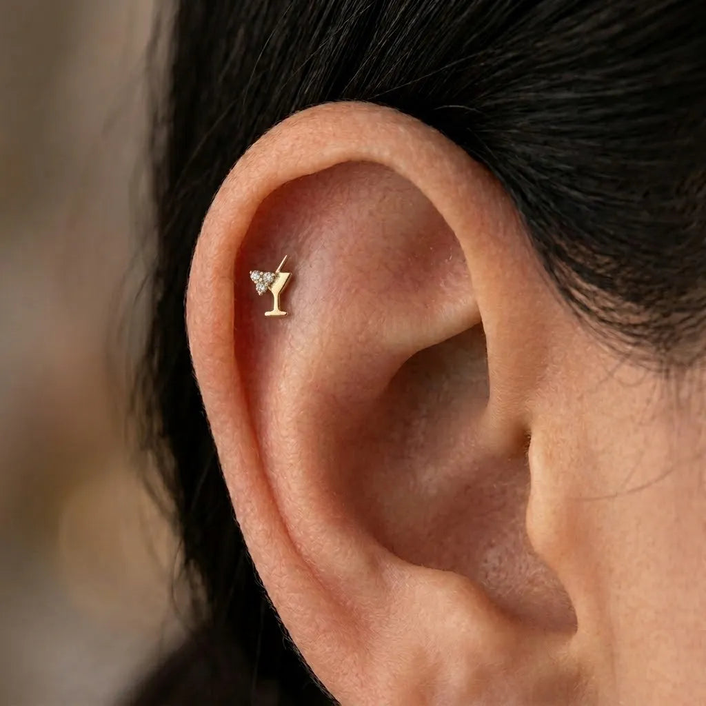 Close-up of ear wearing gold titanium cocktail glass tragus piercing with crystal detail