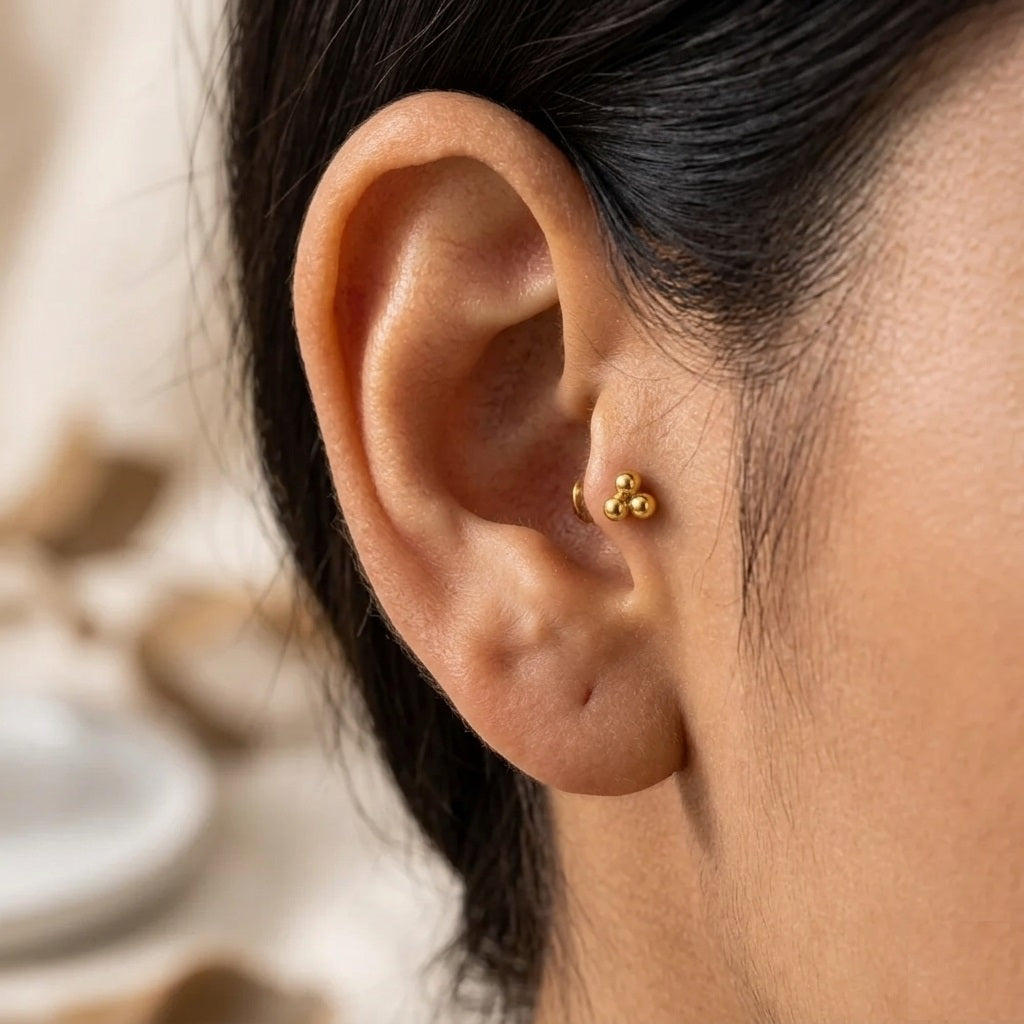 Close-up of an ear wearing a gold earring with a blurred background