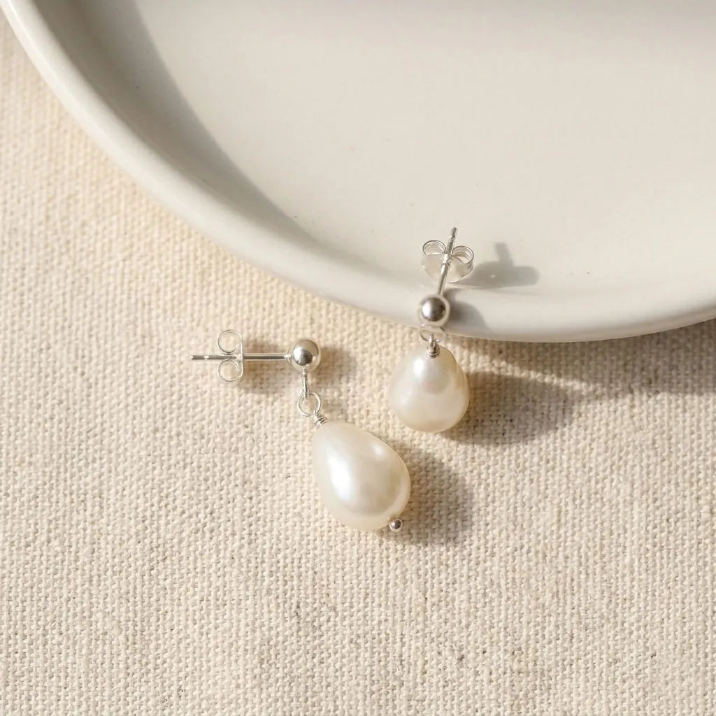 Vita Perlata silver baroque pearl drop earrings flatlay on neutral linen background